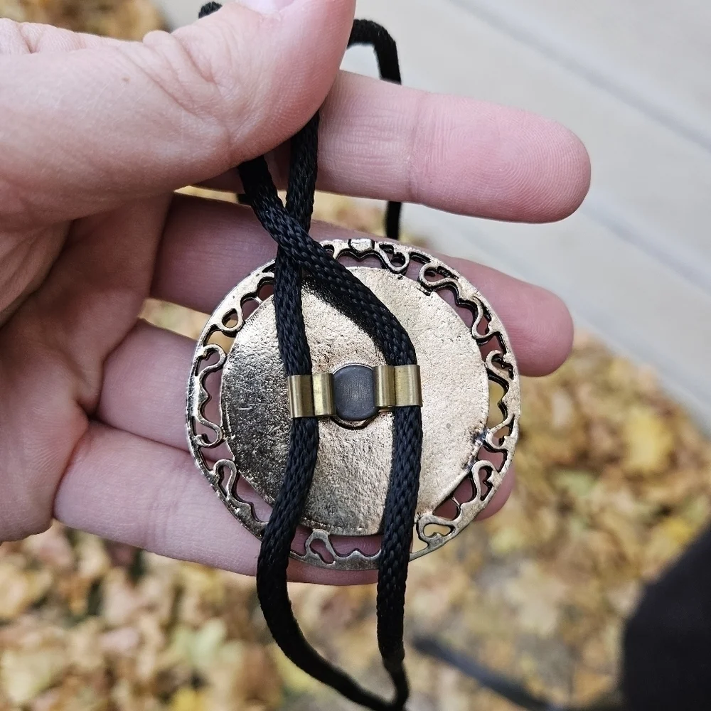 gold tone and brown leather abstract face bolo tie on black cord